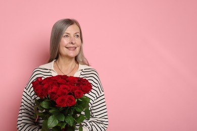 Photo of Smiling woman with bouquet of roses on pink background. Space for text