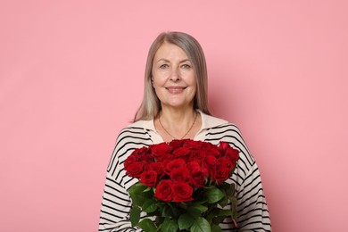 Photo of Smiling woman with bouquet of roses on pink background