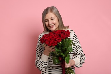 Photo of Smiling woman with bouquet of roses on pink background