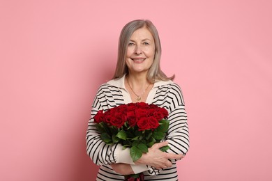 Smiling woman with bouquet of roses on pink background