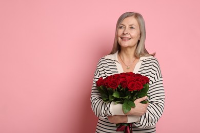 Smiling woman with bouquet of roses on pink background. Space for text