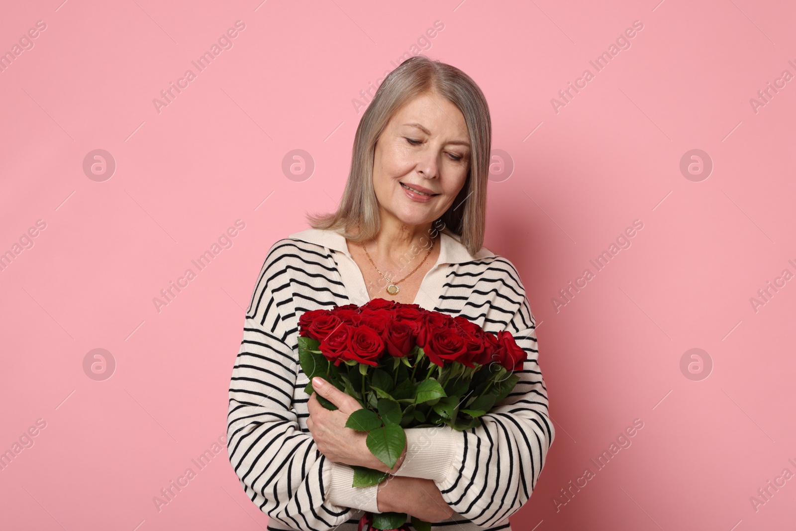 Photo of Smiling woman with bouquet of roses on pink background