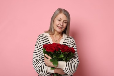 Smiling woman with bouquet of roses on pink background