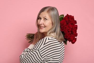 Smiling woman with bouquet of roses on pink background