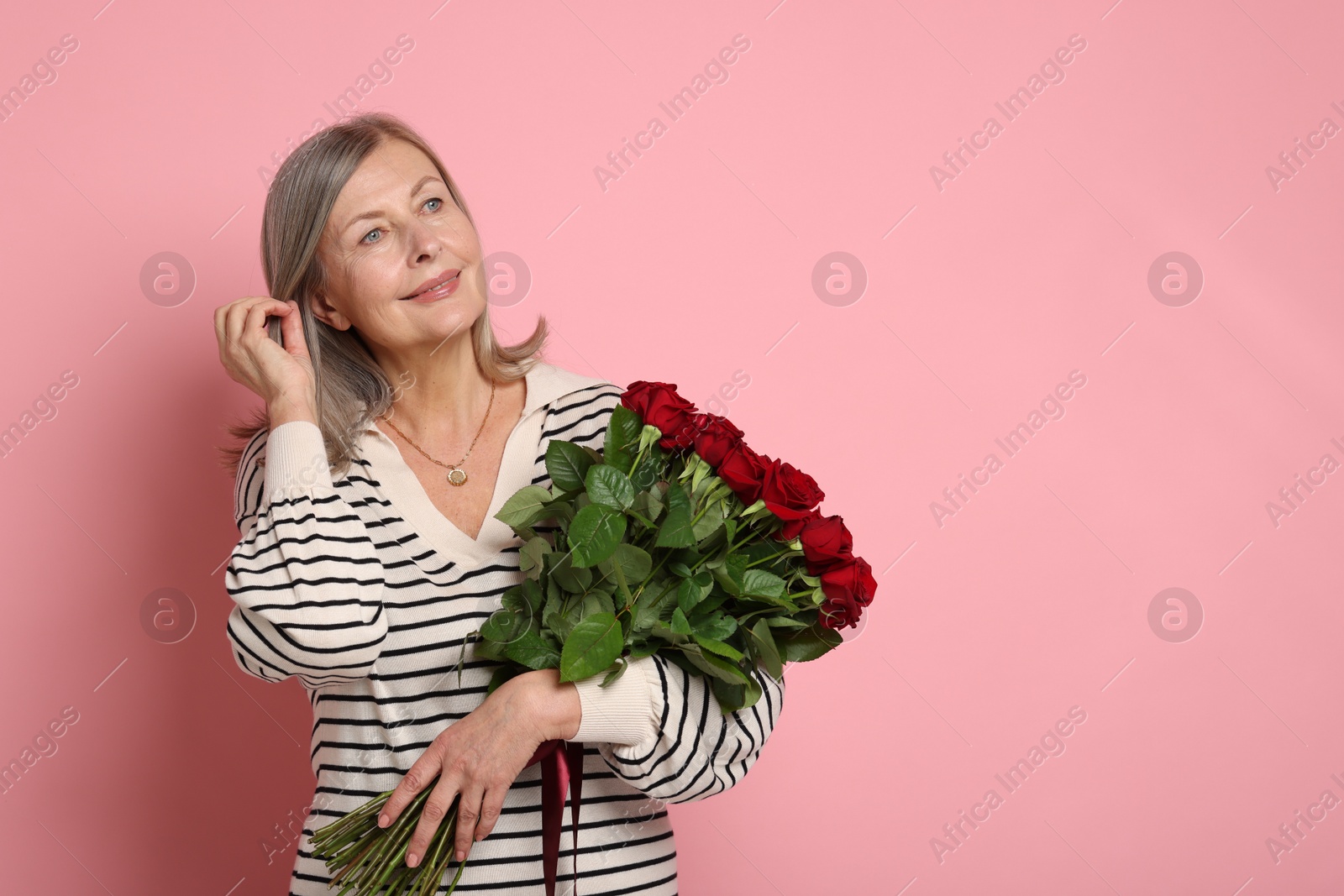 Photo of Beautiful woman with bouquet of roses on pink background. Space for text