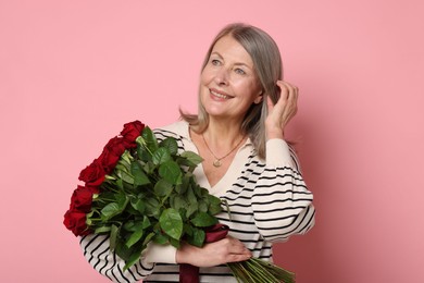 Smiling woman with bouquet of roses on pink background