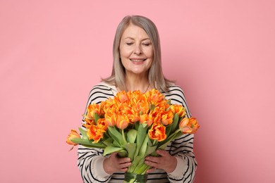 Photo of Smiling woman with bouquet of tulips on pink background