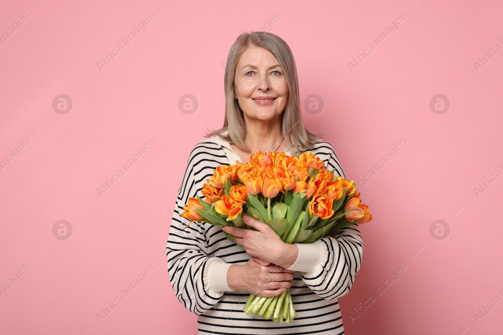 Photo of Smiling woman with bouquet of tulips on pink background