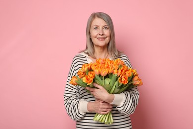 Photo of Smiling woman with bouquet of tulips on pink background