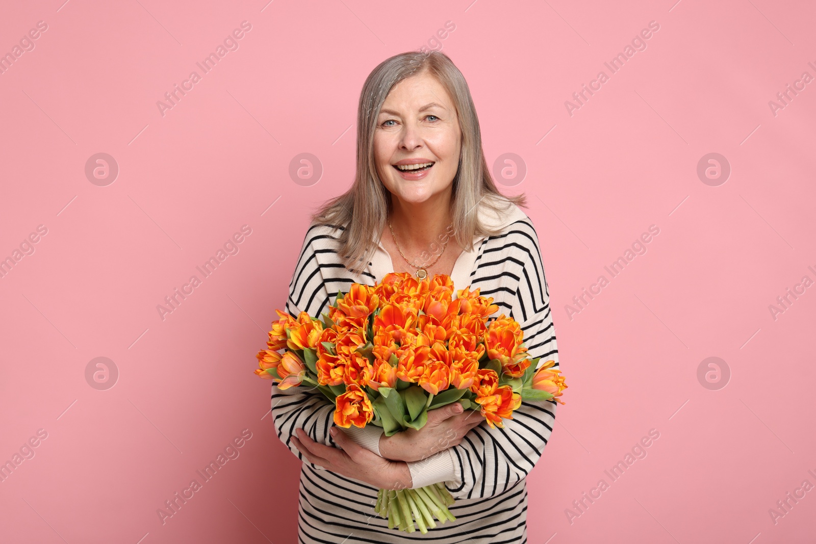 Photo of Smiling woman with bouquet of tulips on pink background