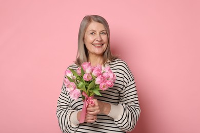 Photo of Smiling woman with bouquet of tulips on pink background