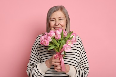 Photo of Smiling woman with bouquet of tulips on pink background