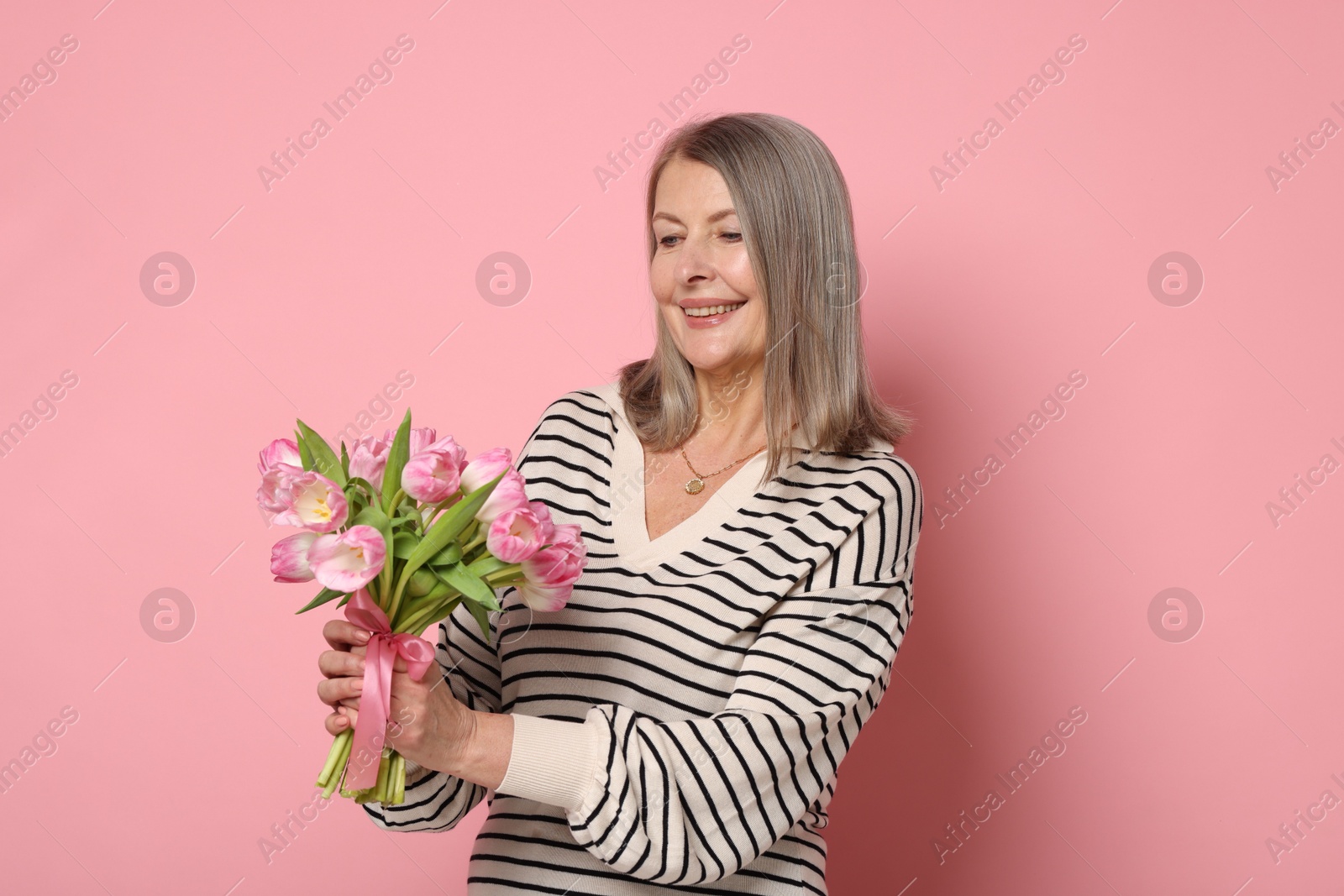 Photo of Smiling woman with bouquet of tulips on pink background