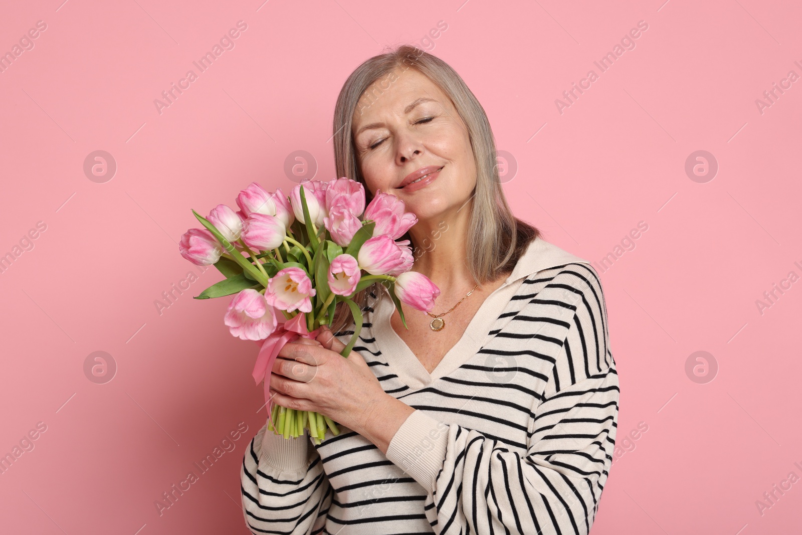 Photo of Beautiful woman with bouquet of tulips on pink background