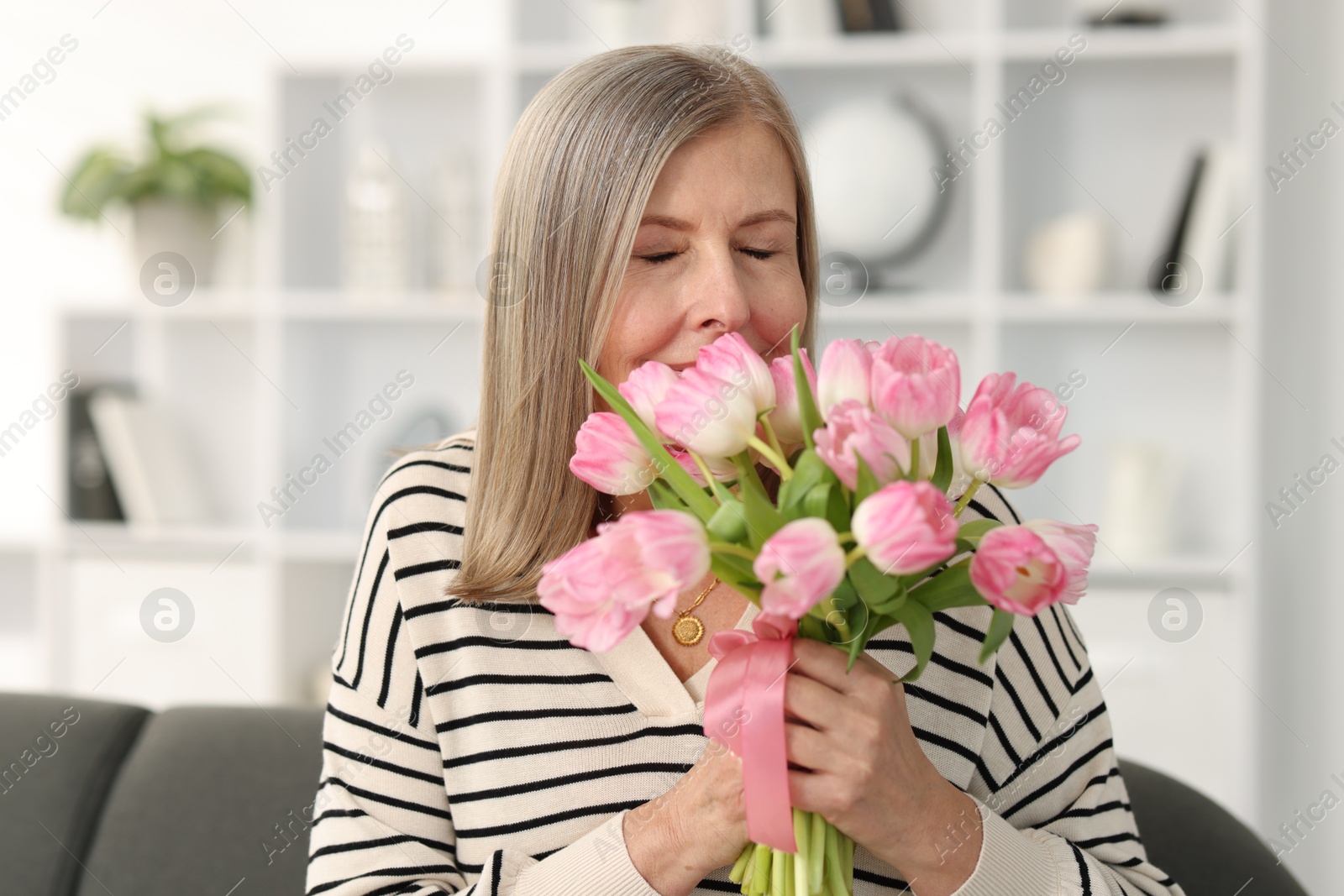 Photo of Beautiful woman with bouquet of tulips at home