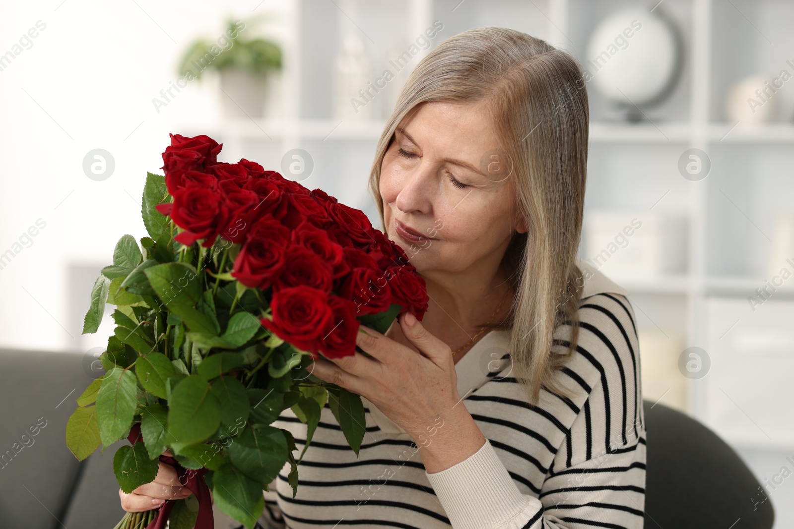 Photo of Beautiful woman with bouquet of roses at home