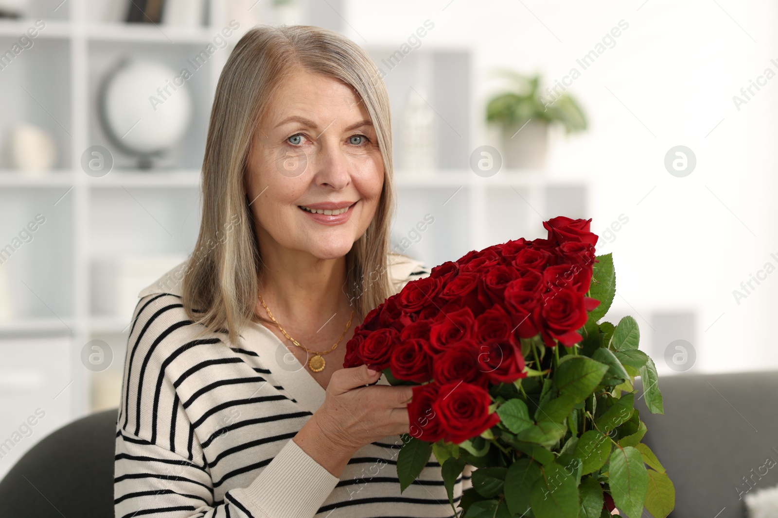 Photo of Smiling woman with bouquet of roses on sofa at home