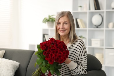 Smiling woman with bouquet of roses on sofa at home