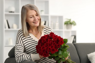 Photo of Smiling woman with bouquet of roses on sofa at home