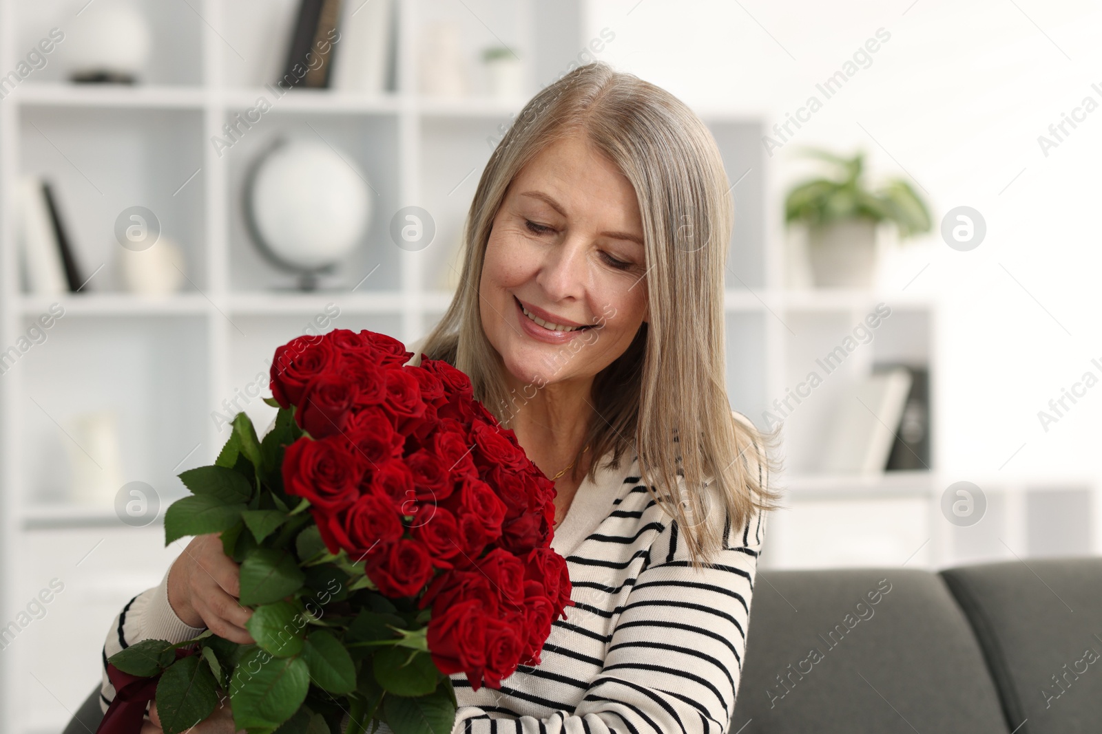 Photo of Smiling woman with bouquet of roses at home