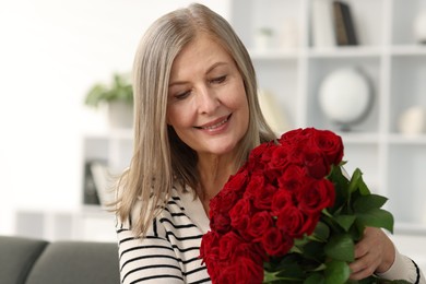 Smiling woman with bouquet of roses at home