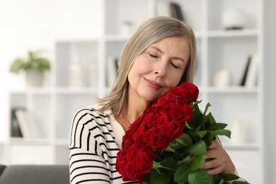 Photo of Beautiful woman with bouquet of roses at home