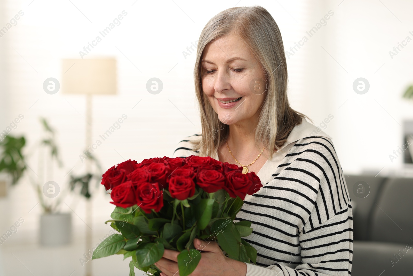 Photo of Smiling woman with bouquet of roses at home