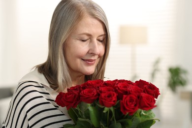 Photo of Beautiful woman with bouquet of roses at home