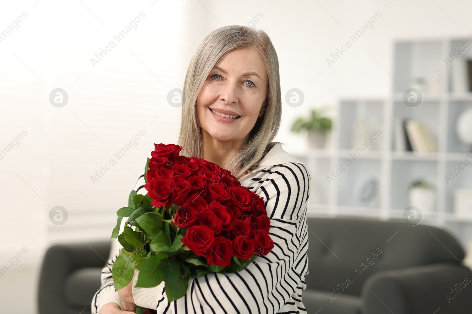 Photo of Smiling woman with bouquet of roses at home