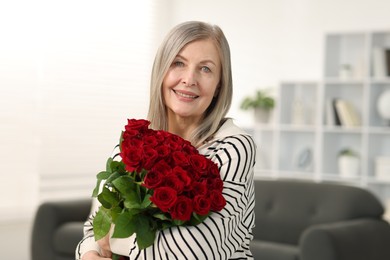 Smiling woman with bouquet of roses at home