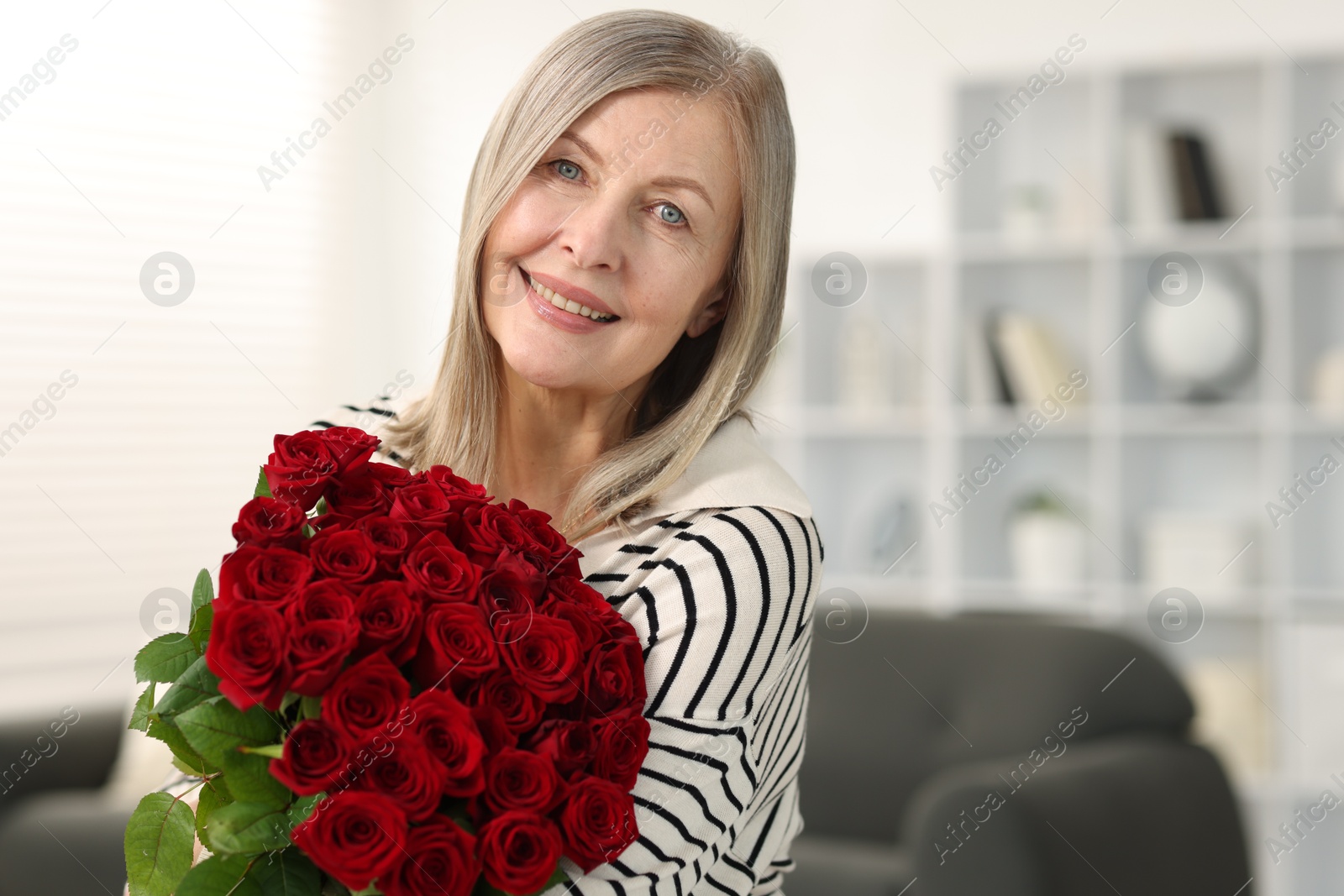 Photo of Smiling woman with bouquet of roses at home