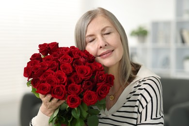 Photo of Beautiful woman with bouquet of roses at home