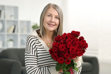 Photo of Smiling woman with bouquet of roses at home