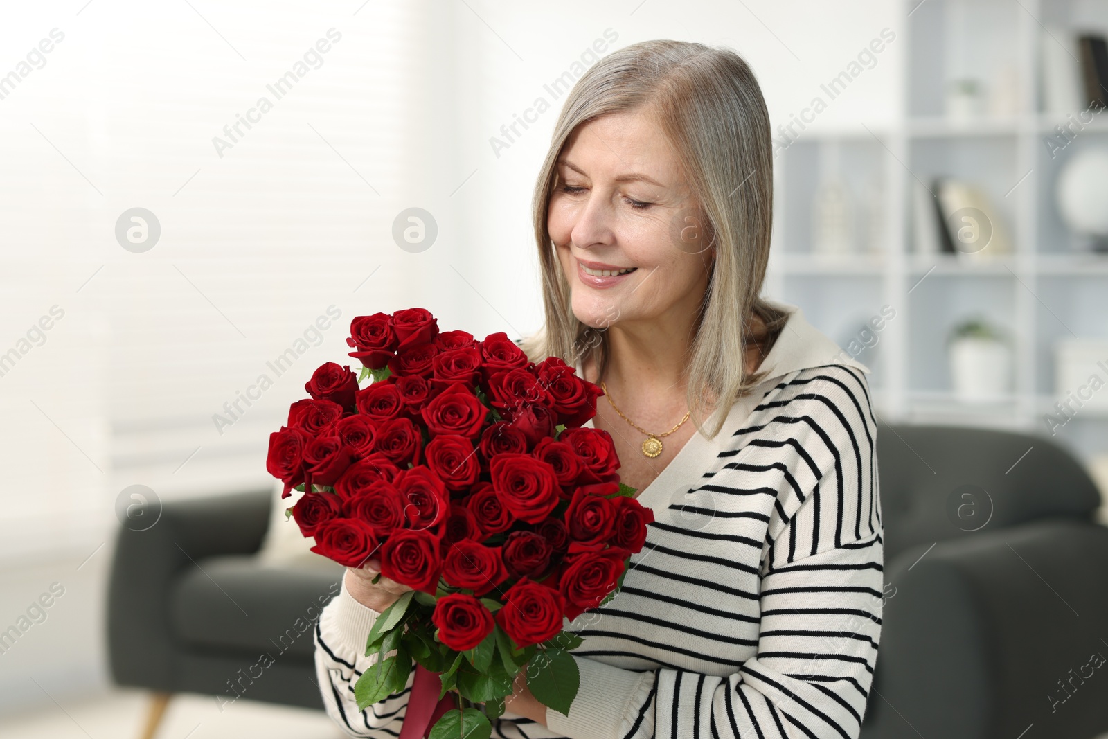 Photo of Smiling woman with bouquet of roses at home