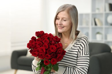 Photo of Smiling woman with bouquet of roses at home