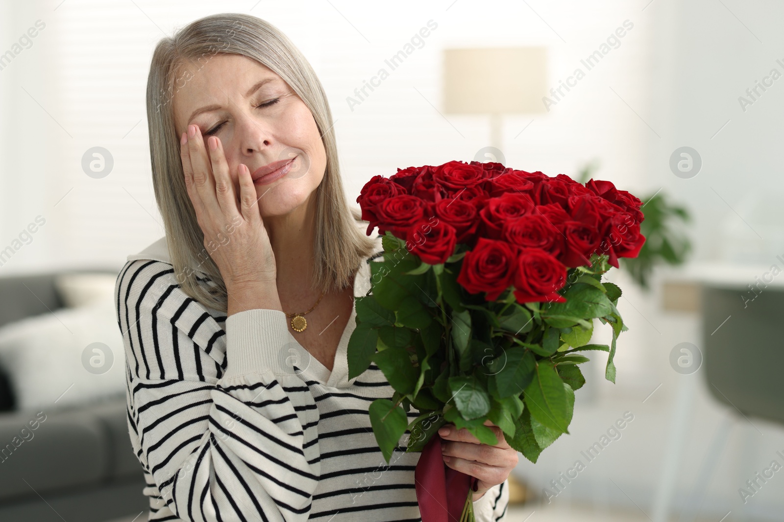 Photo of Beautiful woman with bouquet of roses at home