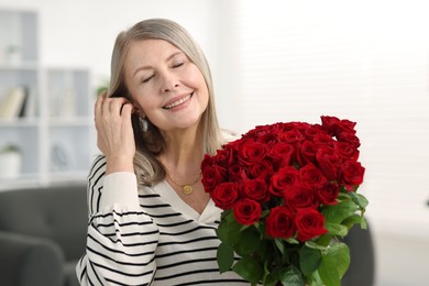 Photo of Smiling woman with bouquet of roses at home