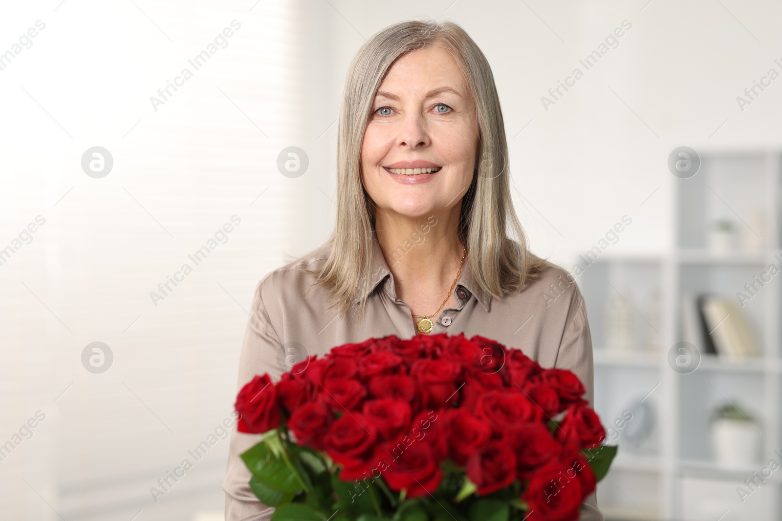 Photo of Smiling woman with bouquet of roses at home