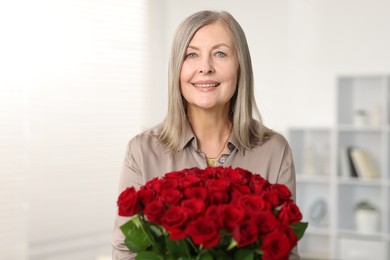 Smiling woman with bouquet of roses at home