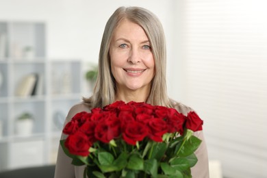 Smiling woman with bouquet of roses at home