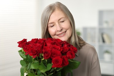 Photo of Smiling woman with bouquet of roses at home