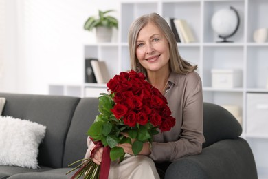 Smiling woman with bouquet of roses on sofa at home