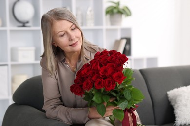 Beautiful woman with bouquet of roses on sofa at home