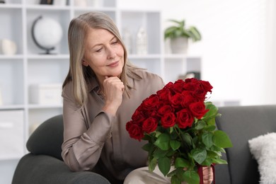 Photo of Beautiful woman with bouquet of roses on sofa at home