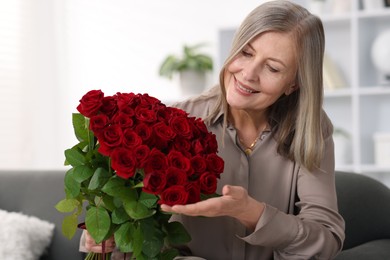 Photo of Smiling woman with bouquet of roses on sofa at home