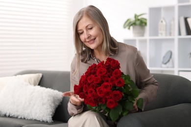 Photo of Smiling woman with bouquet of roses on sofa at home