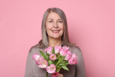 Photo of Smiling woman with bouquet of tulips on pink background