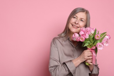 Photo of Smiling woman with bouquet of tulips on pink background. Space for text