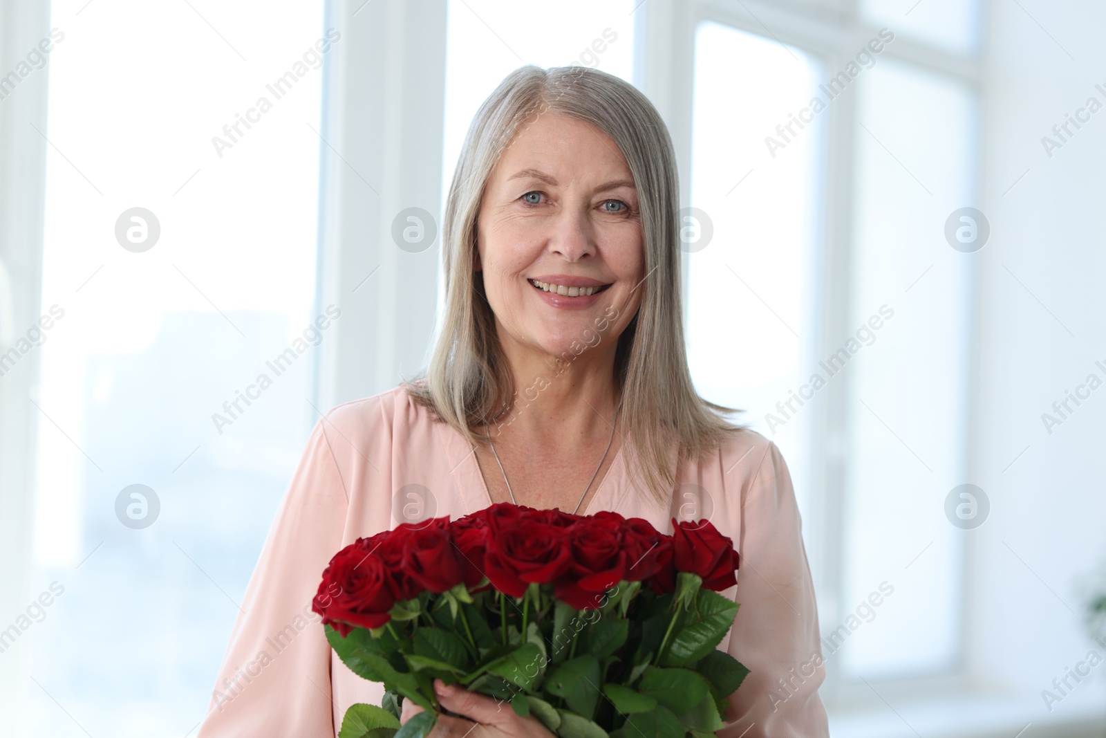 Photo of Smiling woman with bouquet of roses at home