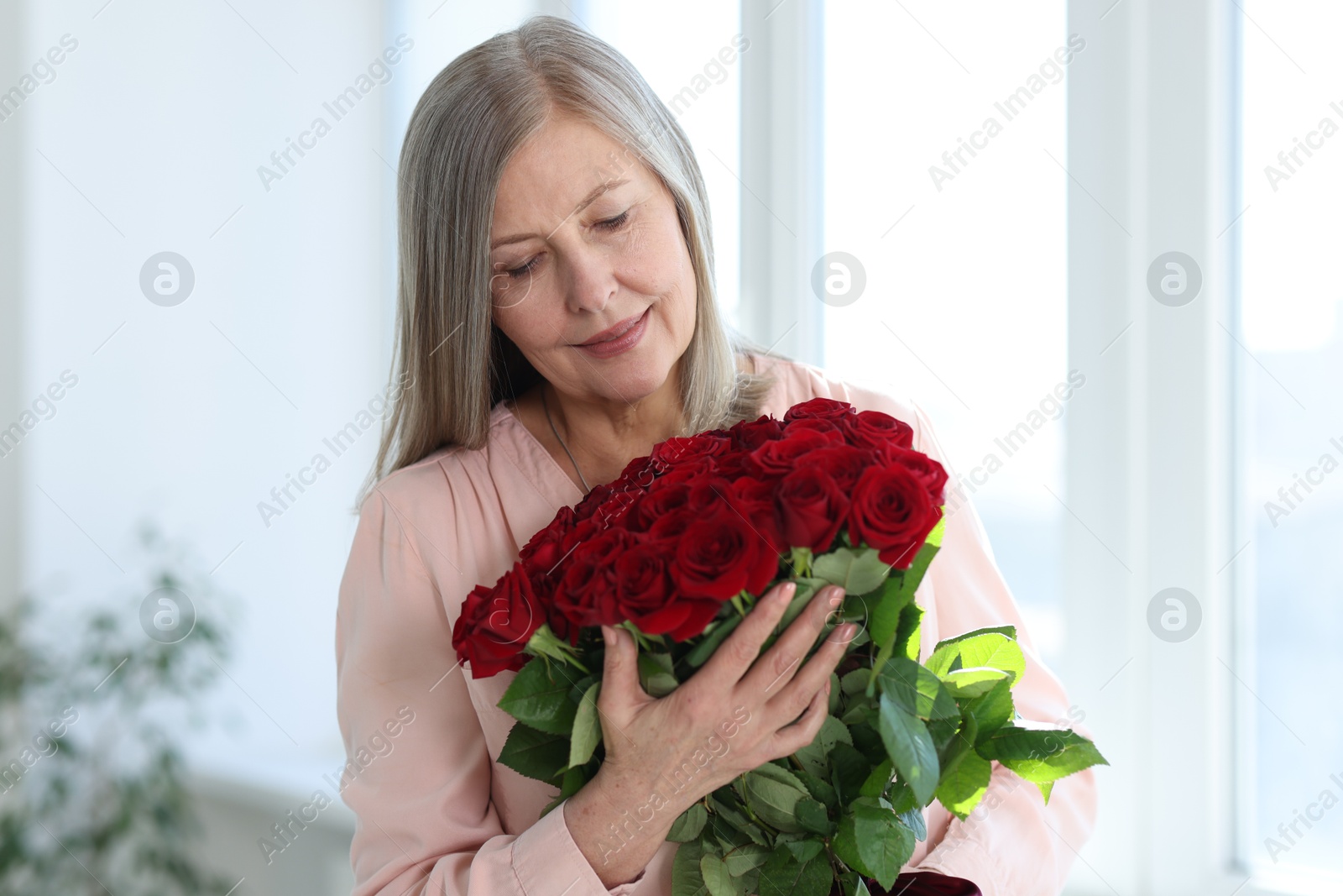 Photo of Beautiful woman with bouquet of roses at home